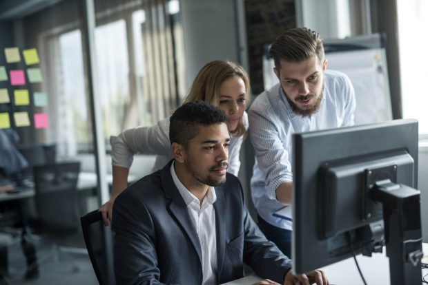 Three people looking at a computer screen and talking