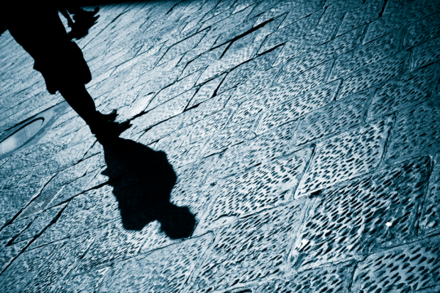 A photo of someone shadow walking down pavement on dark street