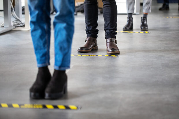 Image of people's feet in a socially distanced queue