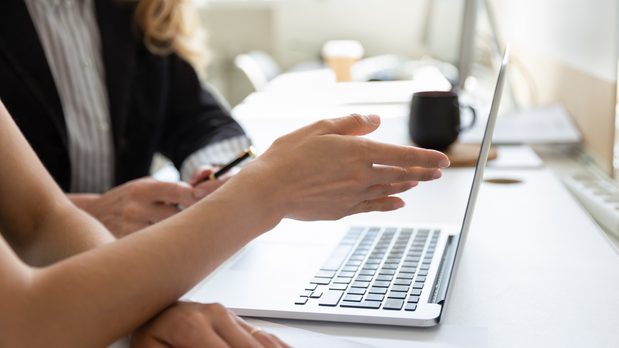 Two people sat besides a laptop and pointing towards the screen, having a discussion